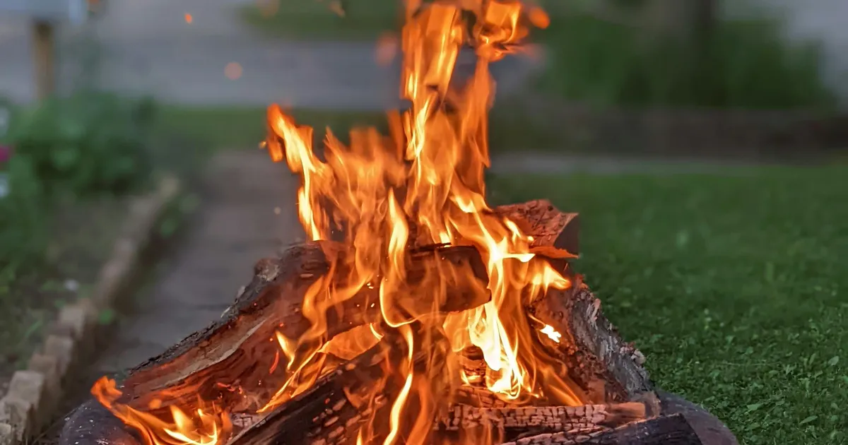 Corten weathering steel portable fire bowl on flagstone patio with surrounding chairs